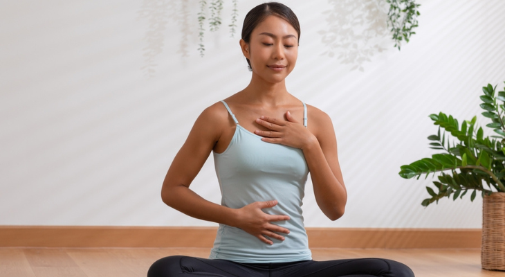 Woman practices her breathing while sitting on the floor.