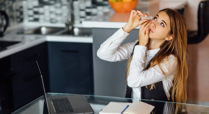 Woman uses eyedrops in the kitchen.