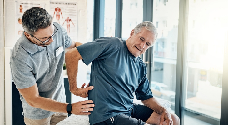 Old man has back pain addressed by chiropractor.