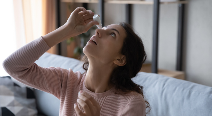 Woman puts eye drops in her eyes.