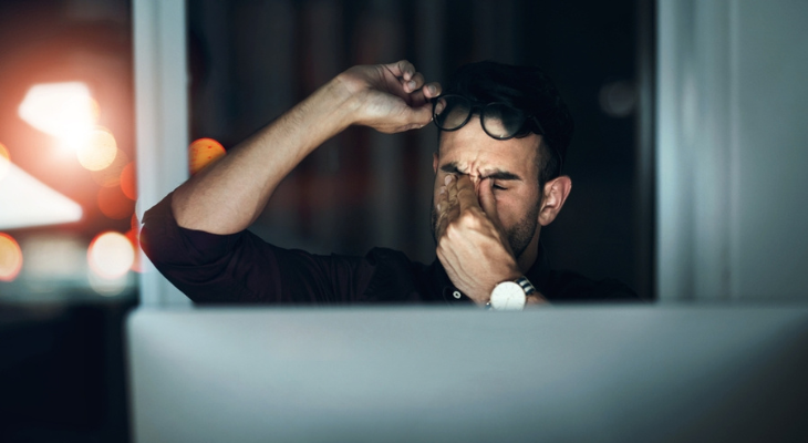 Man rubs his sore eyes.