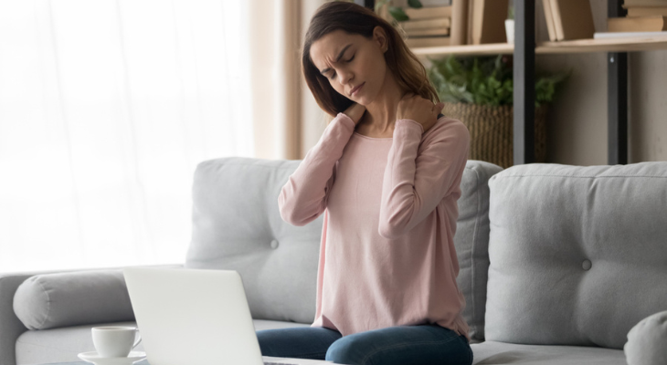 Woman experiences neck pain from working on her couch.