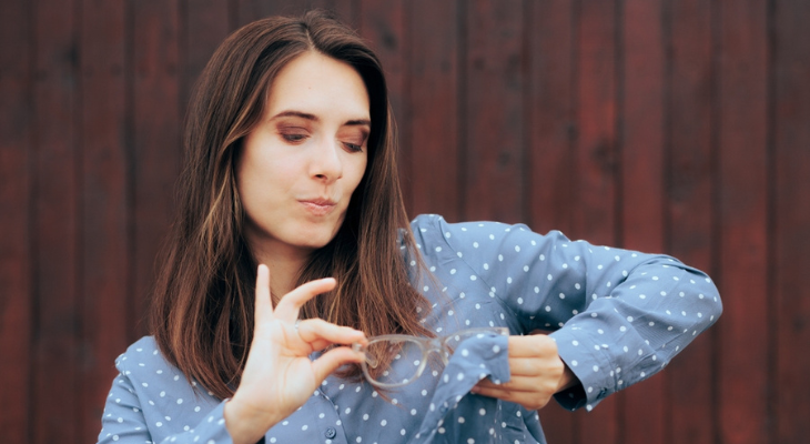 Woman cleans her glasses the wrong way.
