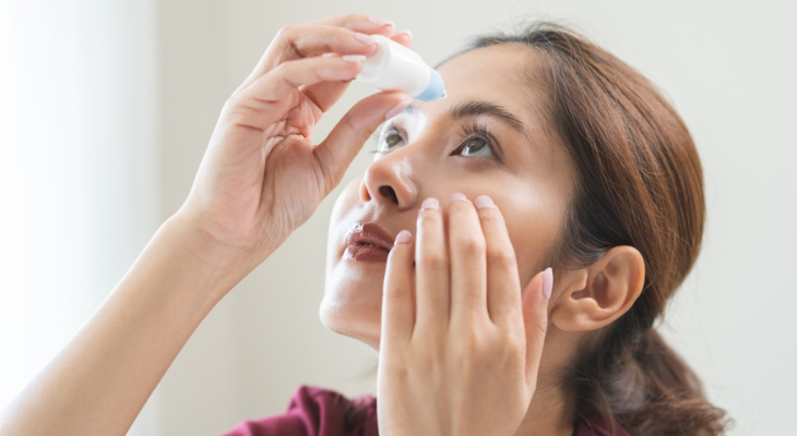 Asian woman uses eye drops.