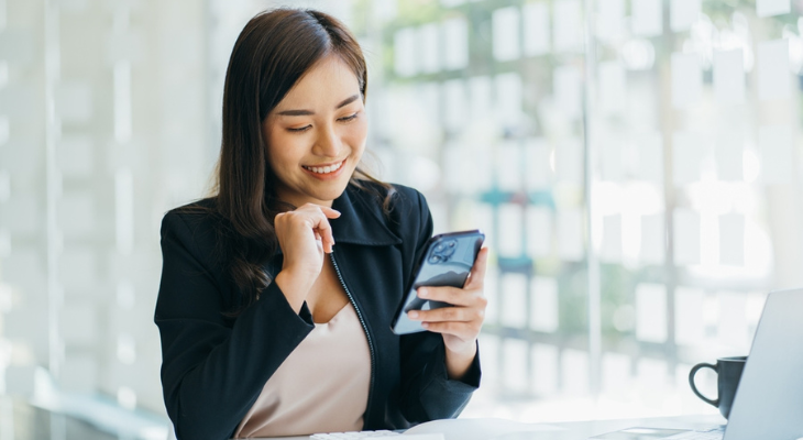 Woman smiles at her phone.