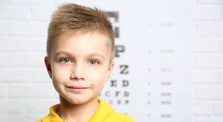 Little boy standing in front of eye chart 