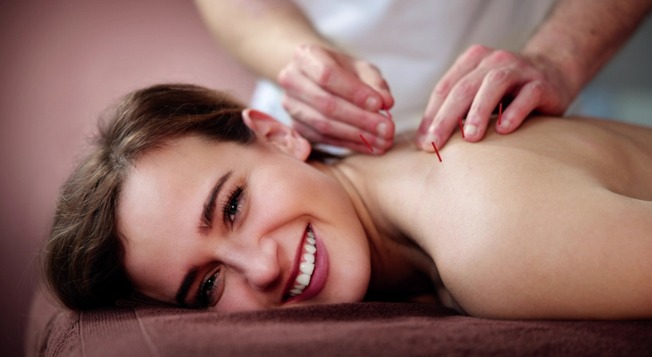 Happy woman receives acupuncture.