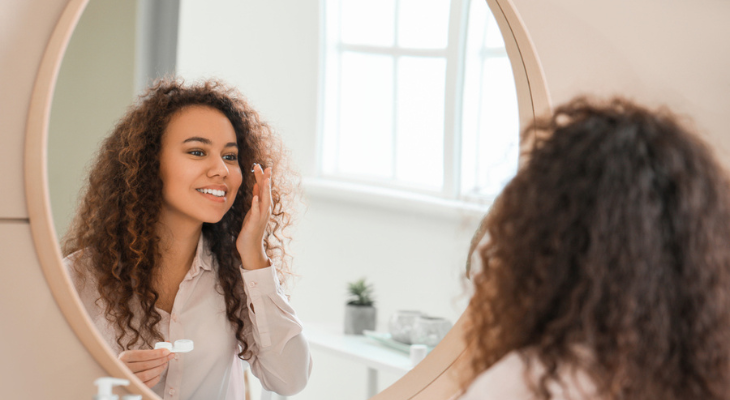 Young woman puts in contact lenses