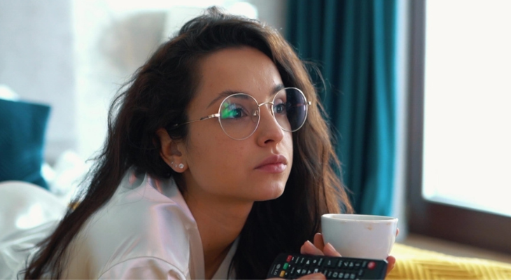 Woman watches television while modeling glasses.