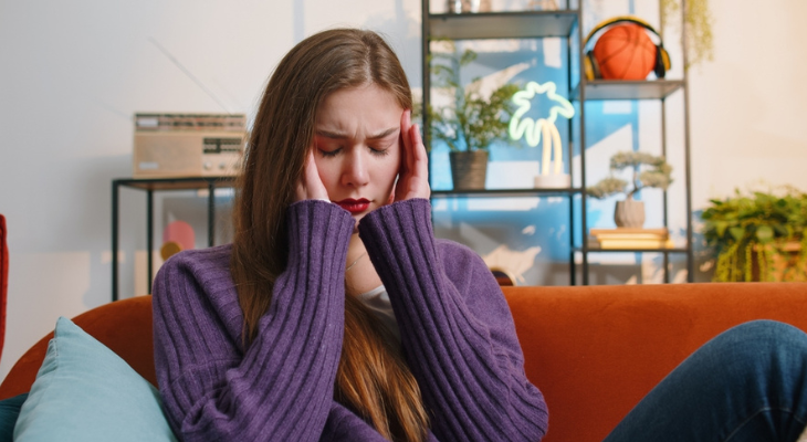 Young woman holds her head in pain.
