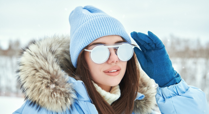 Woman in the snow wear sunglasses to protect her eyes.