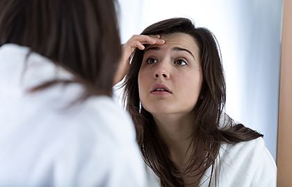 acne-hair-care-products-woman-checking-acne-on-forehead.jpg