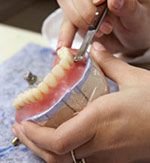 hands sculpting dentures in lab making dentures Plainview, NY