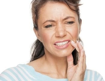 woman holding jaw in pain, emergency dental care Baton Rouge, LA dentist