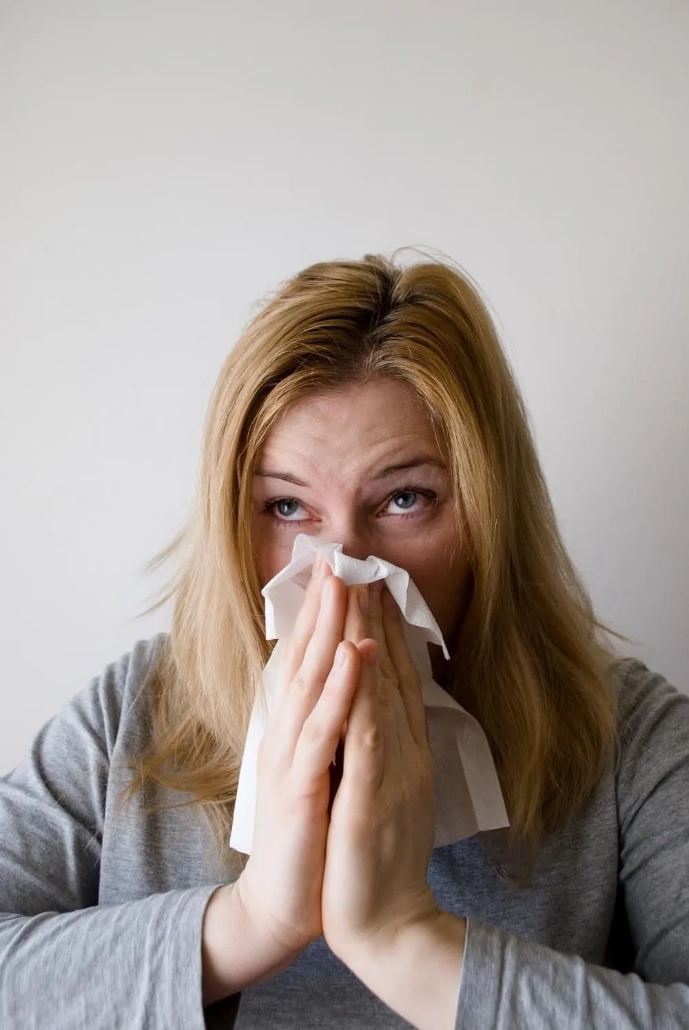 A Woman Sneezing into a Tissue