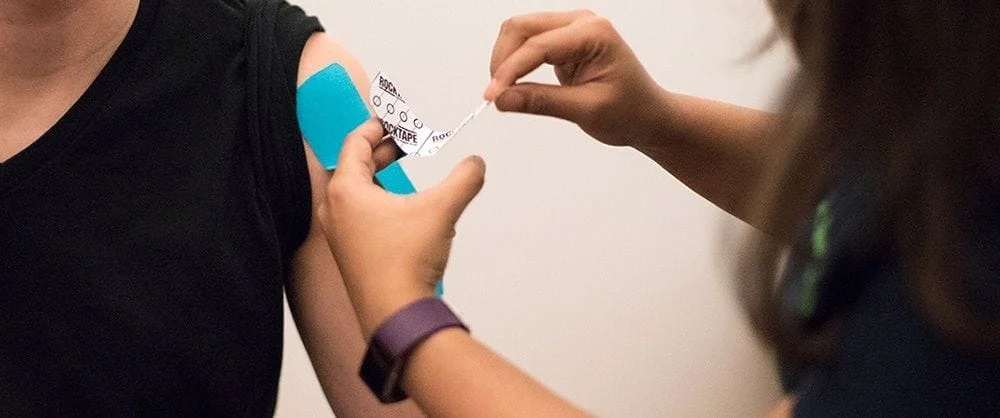 kinesio taping a patient suffering from muscular pain from a workout injury