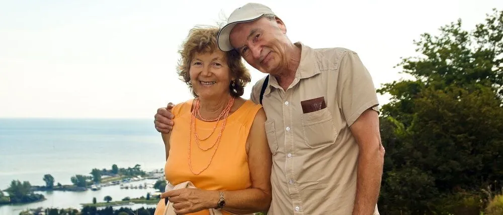 Elderly couple smiling and hugging on a hike