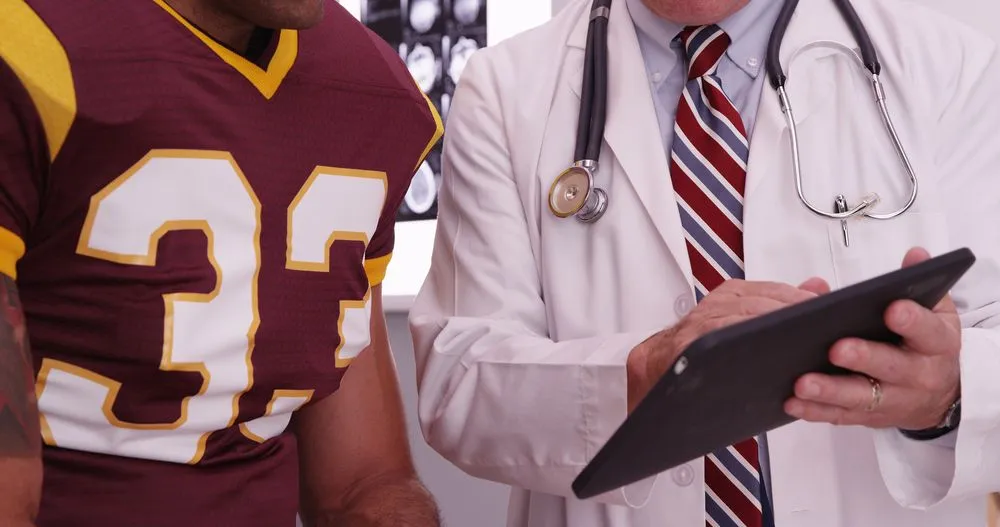 injured football player talking to his chiropractor