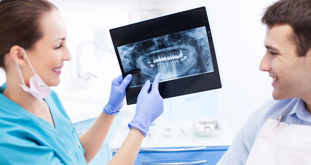 female dental assistant showing male patient x-ray of mouth, general dentist Frederick, MD