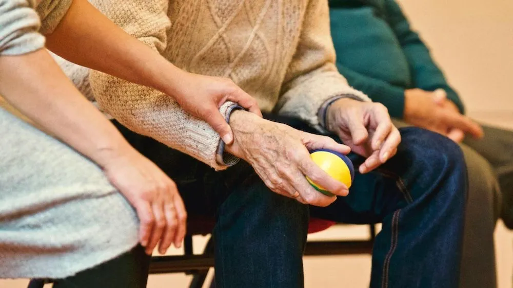 young woman holding hand with senior holding a ball while sitting