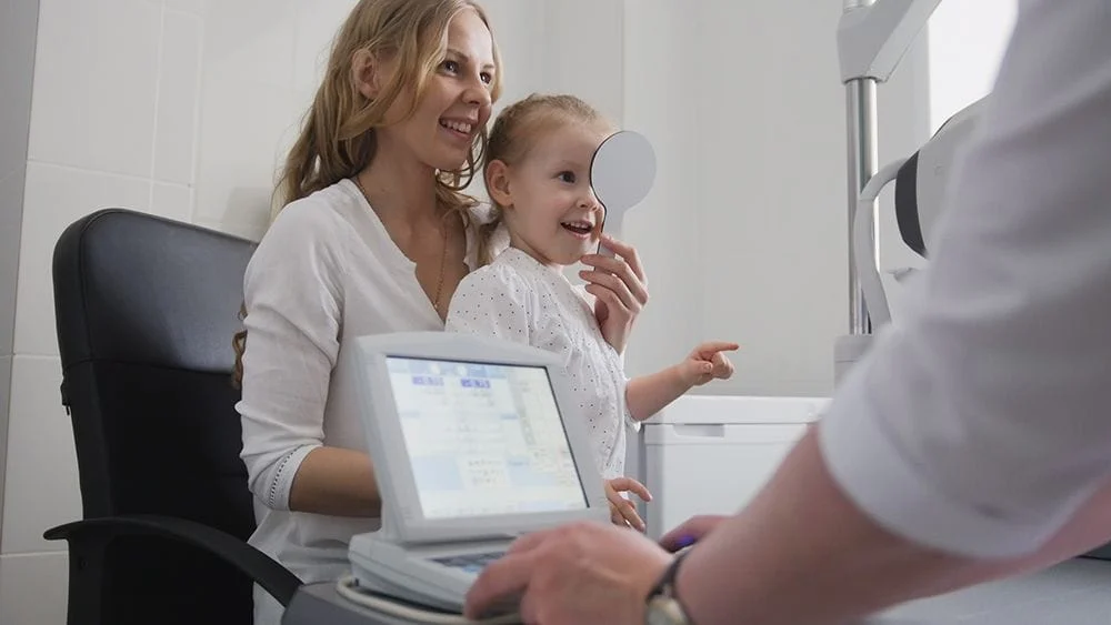 Mom helping her daughter through a pediatric eye exam.