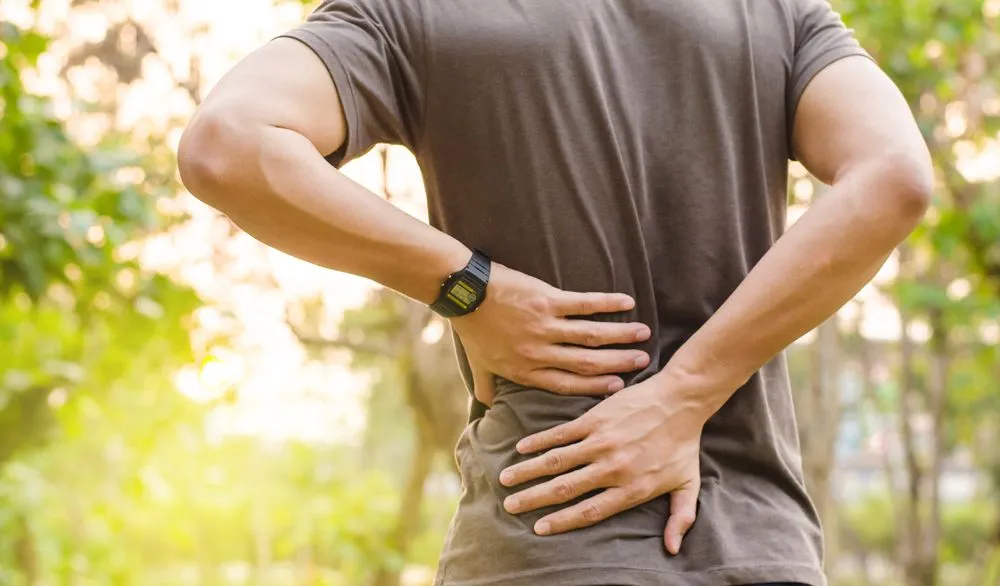 man holding his back from pain from a lower back sprain