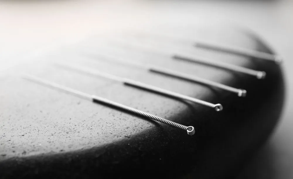 Acupuncture needles on a soothing massage stone.