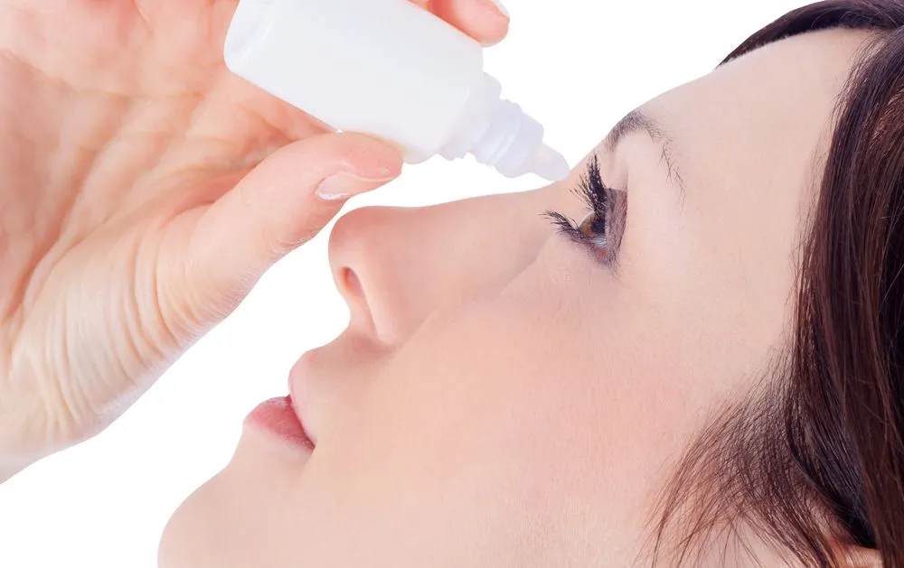 woman putting eyedrops on her eye