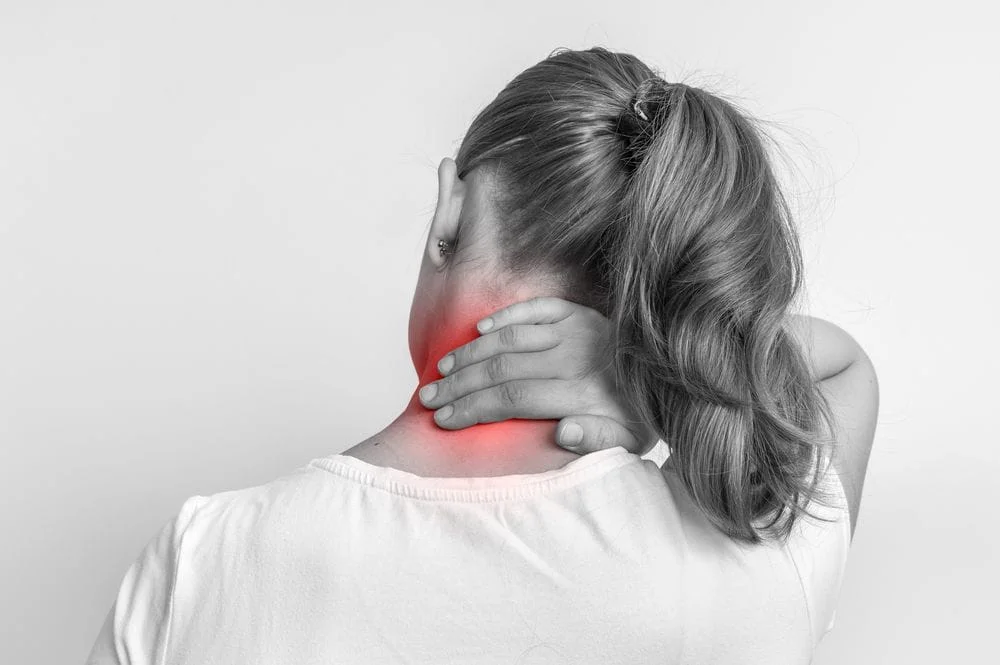 woman with neck pain holding the back of her neck