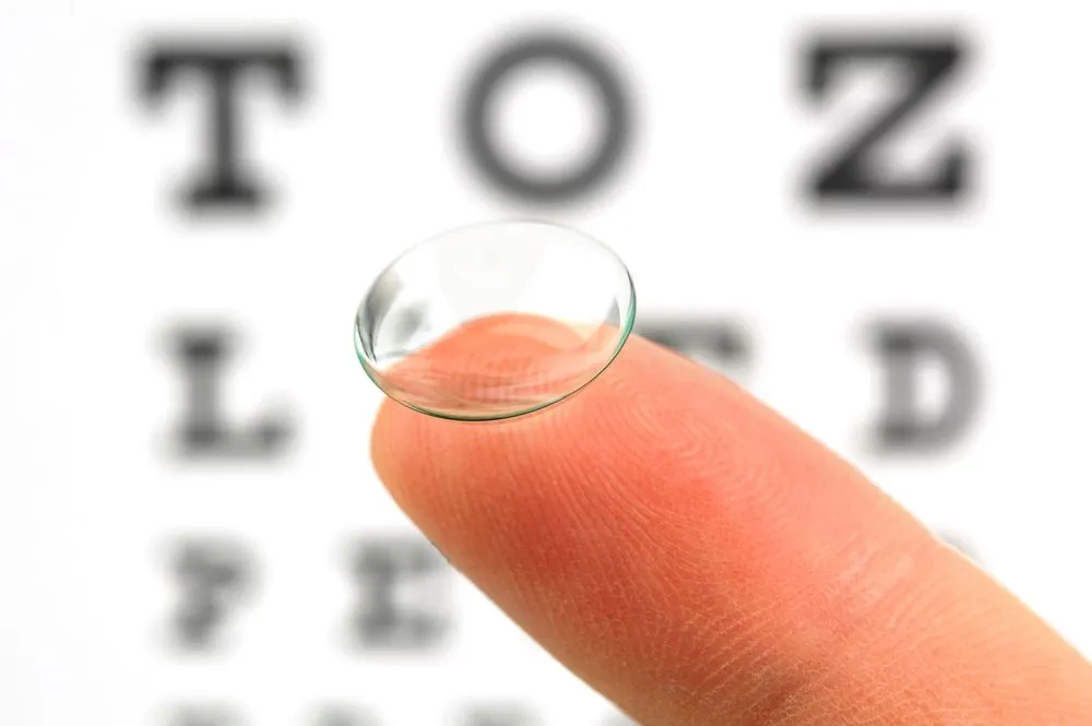 Woman holding disposable contact lenses.