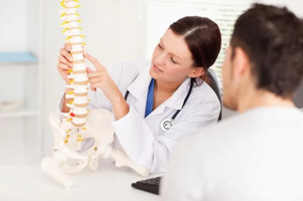 Chiropractor going over possible bulging discs that occur in the spine