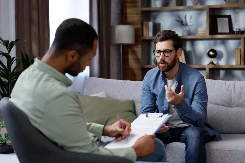 Therapist talking to a man sitting on a couch