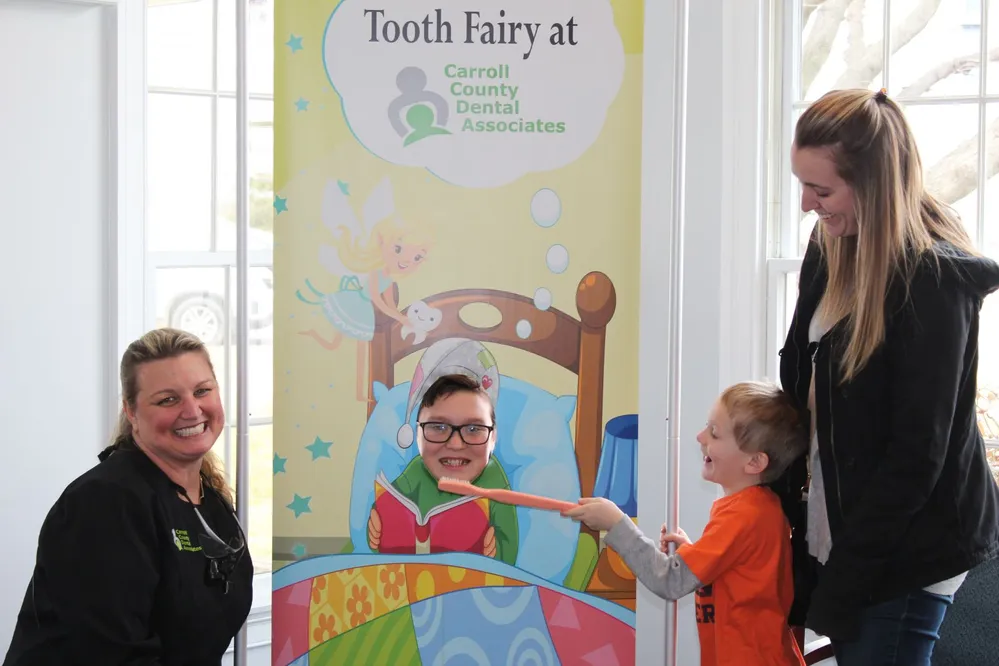 dentist and children posing with tooth fairy sign at Carroll County Dental Associates office, family dentist Westminster, MD