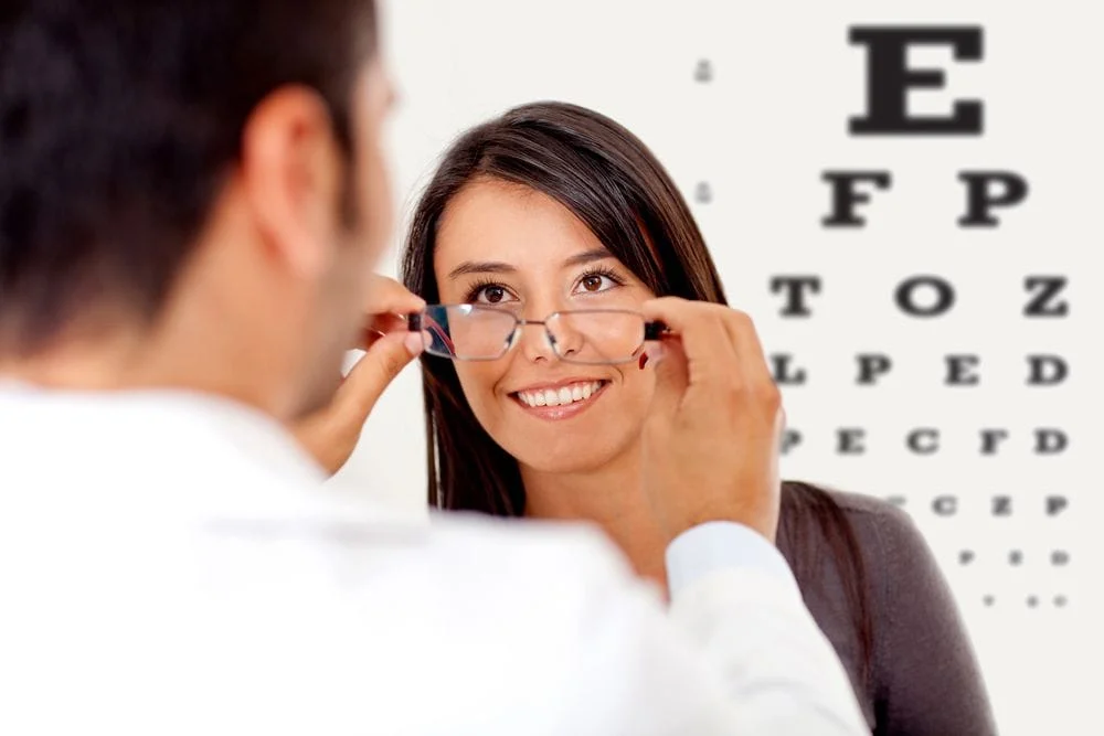 optometrist fitting glasses on woman