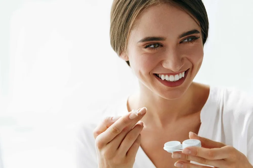 woman holding contact lens on finger