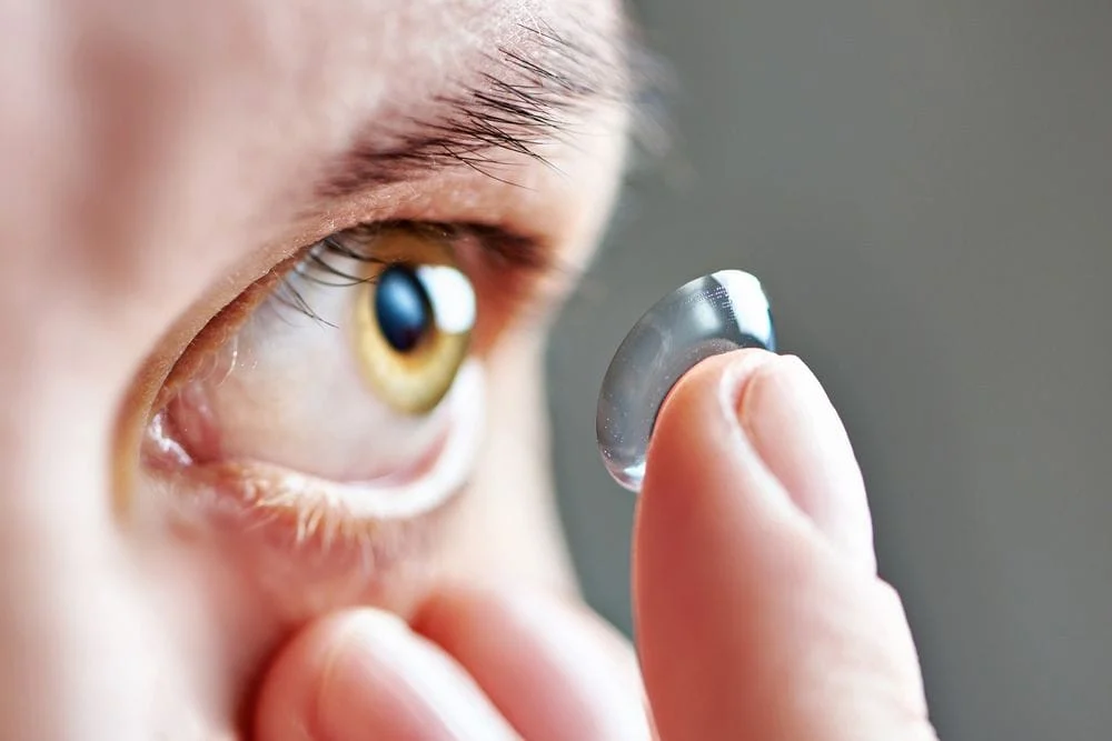 woman inserting contact lens into eye
