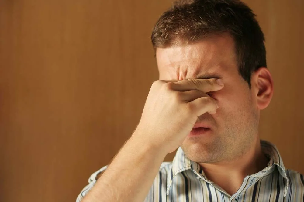 man rubbing his eyes from eye allergies