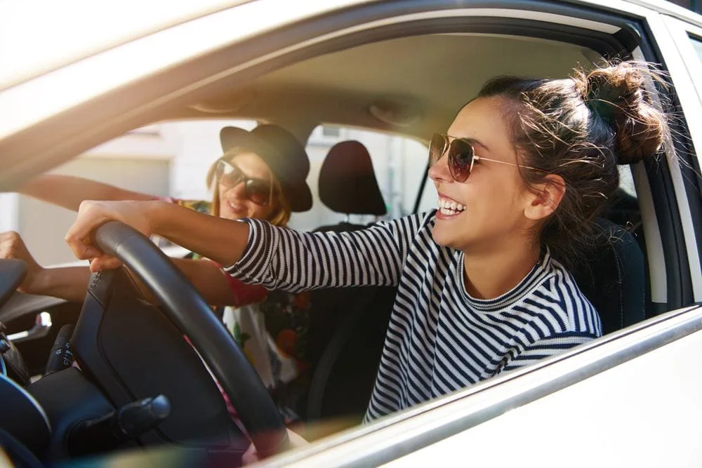 young women riding in a car wearing sunglasses