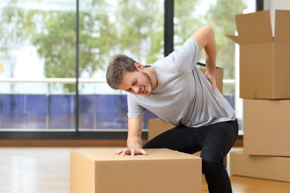 Man with back pain carrying boxes