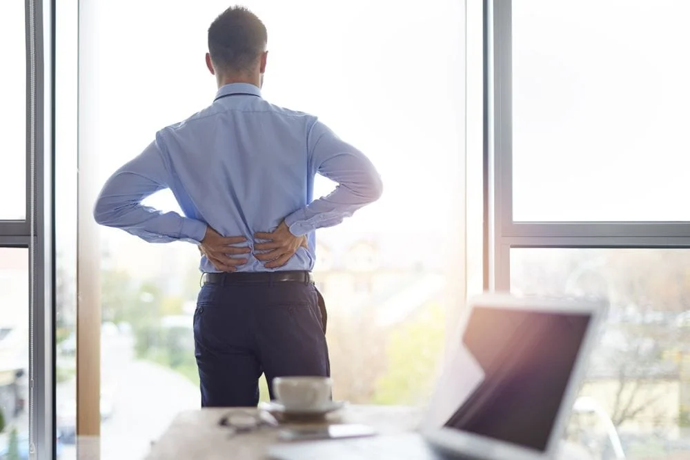 man suffering from lower back pain in his office