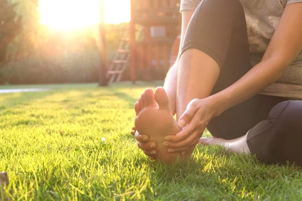 Woman with Plantar Fasciitis holding her foot outside.