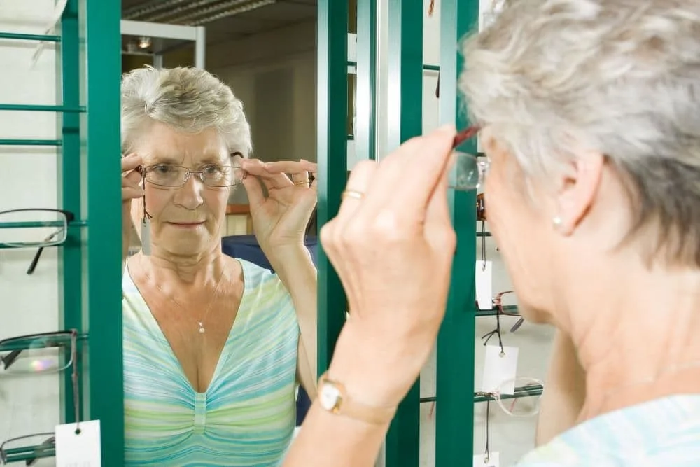 Woman looking in the mirror with her new glasses
