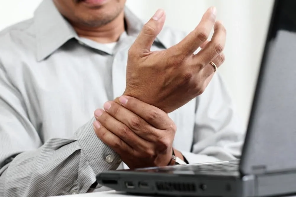 Man with wrist pain, at work who needs chiropractic care.