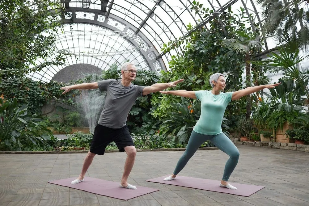 Couple practicing yoga in beautiful atrium with lots of plants