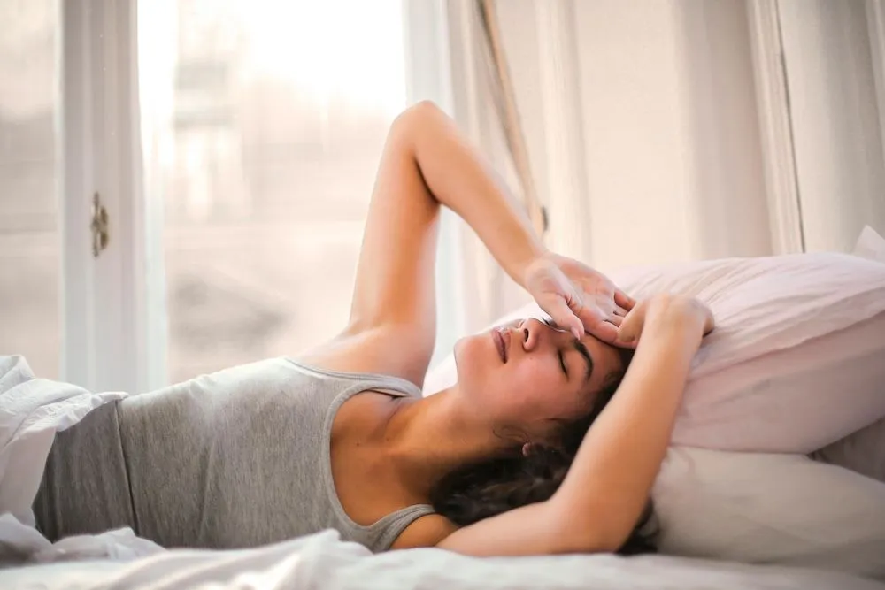 woman lying on bed with headache