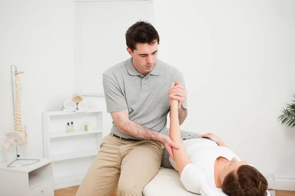 patient is at a chiropractor learning about Fibromyalgia Symptoms and how chiropractic care can help her manage it