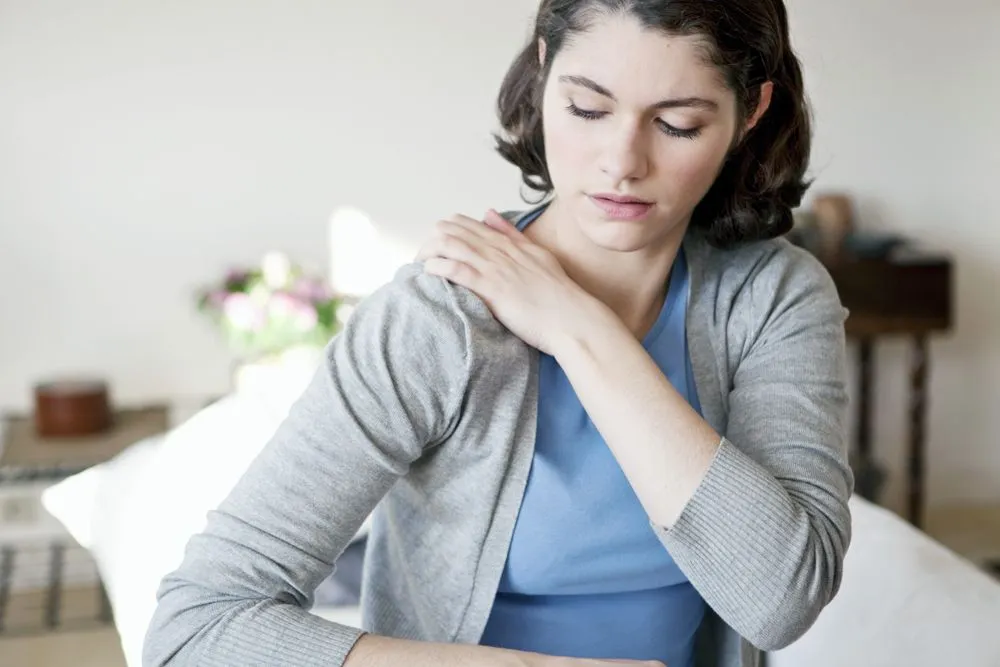 female patient with holding her shoulder in pain