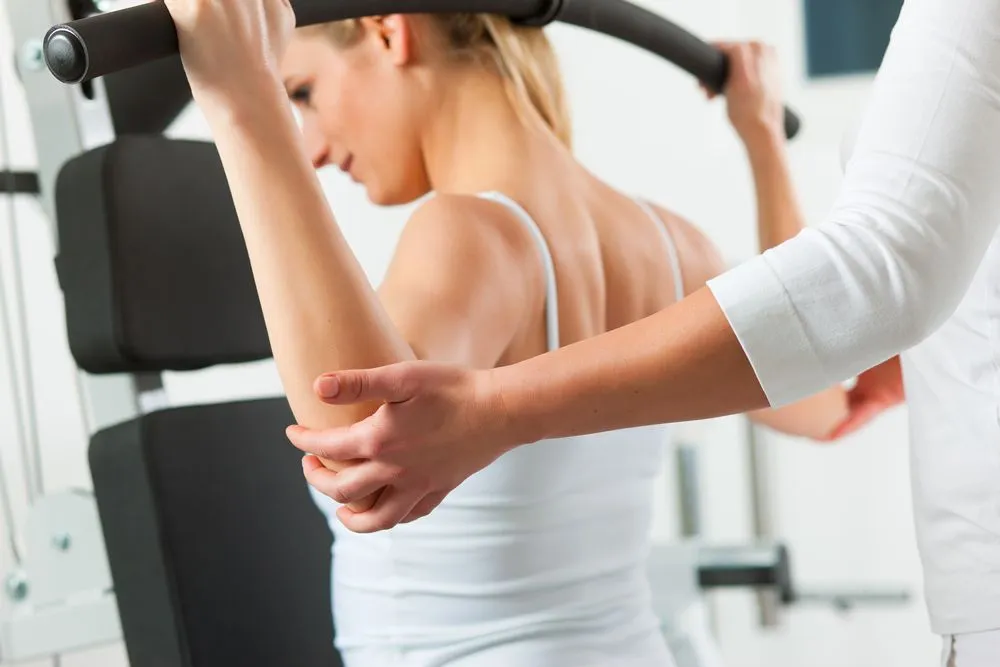 Chiropractor helping woman with weight-lifting exercise to help with her weight loss program