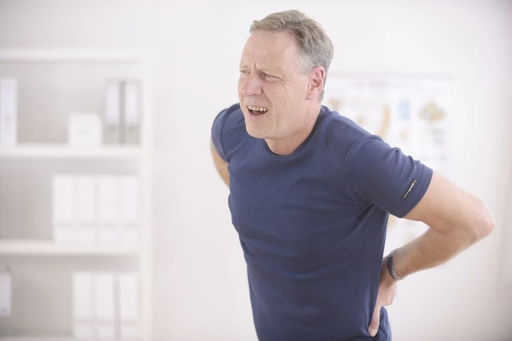 man holding his lower back in discomfort