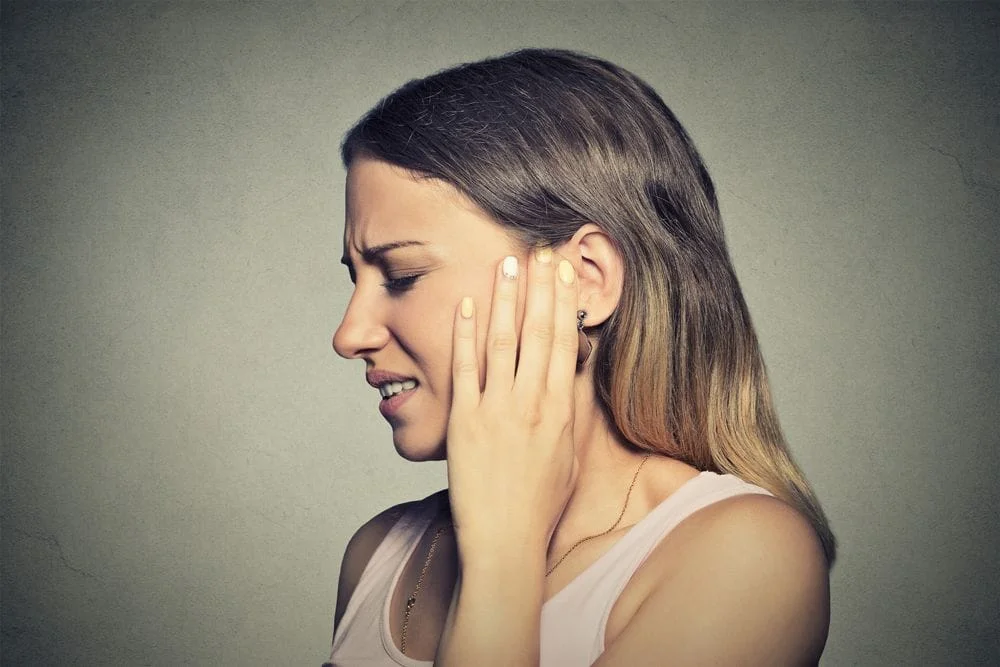 woman holing her jaw in pain from TMJ